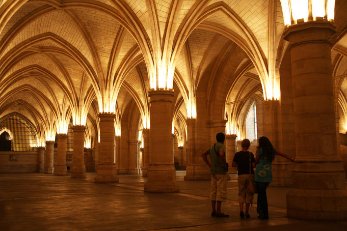 Visitors in Salle des Gens d'Arms (Hall of the Men-at-Arms), part of La Conciergerie, a historical royal palace and prison.