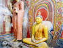 Seated Buddha statues with flower offerings.