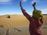 Tuareg man guiding 4WD car through soft sand dune.