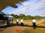 Crew watching small plane landing on runway, South West Costa Rica.