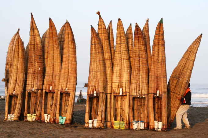 A man specially employed to lift Caballitos de Totora (small reed boats) carrying a fishermans craft to the waters edge, Lambayeque