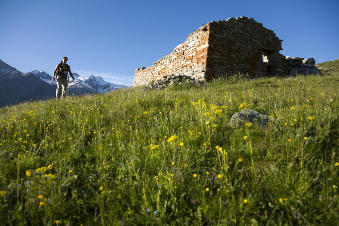 Woman passing abandoned farmhouse in Vallone Lauson on the trail from Valnontey to Rifugio Vittorio Sella.
