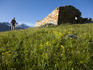 Woman passing abandoned farmhouse in Vallone Lauson on the trail from Valnontey to Rifugio Vittorio Sella.