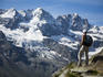 Hiker on traverse from Refugio Vitorio Sella to Herbetet with mountains of Gran Paradiso massif in background.