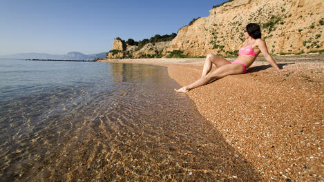 Girl sunbathing on Spiaggia Sos Dorroles beach shore, Cala Gonone.