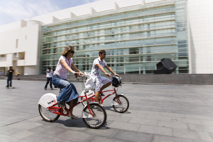 Women riding city council bikes through town, Barcelona