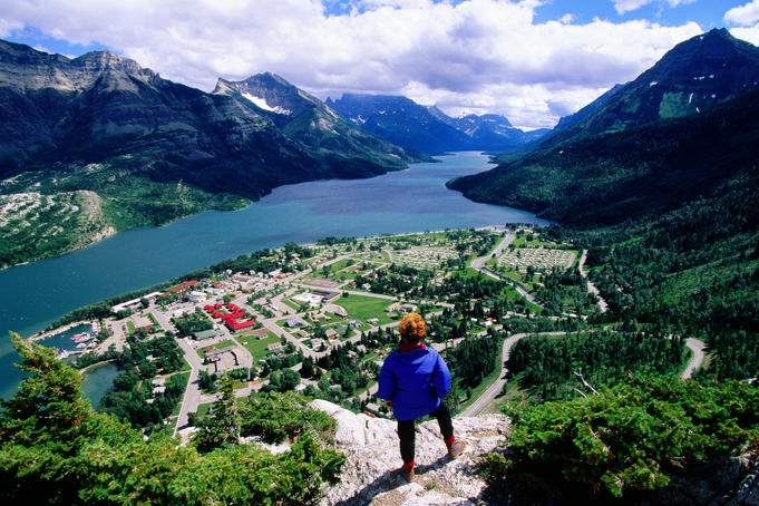 Hiker overlooking Waterton town, Waterton Lake and Canadian Rockies from Bear Hump.