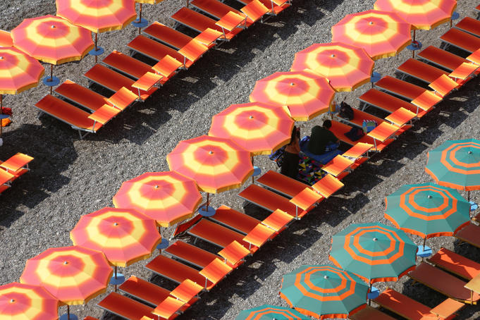 Beach umbrellas and chairs lining black sand beach, Amalfi Coast.