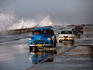 Cars negotiating wet conditions along the Malecon as huge hurricane-powered waves crash over sea wall. Havana, Cuba.