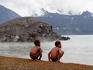 Children watching active volcano Mt Tuvurvur fuming above harbour, near Rabaul.