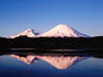 Parinacota and Pomerape volcanoes at sunset, with reflection in high-altitude lake, Norte Grande region.