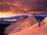 Climber on orange-tinted glacier above Ishinca Valley at sunset, Cordillera Blanca range.