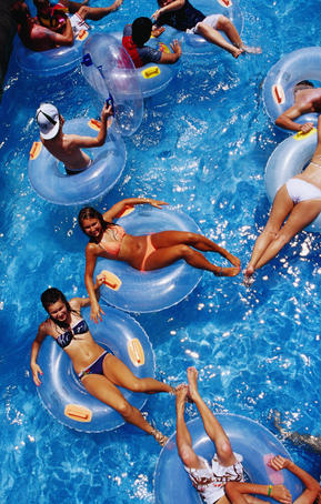 People floating in pool on rubber rings.