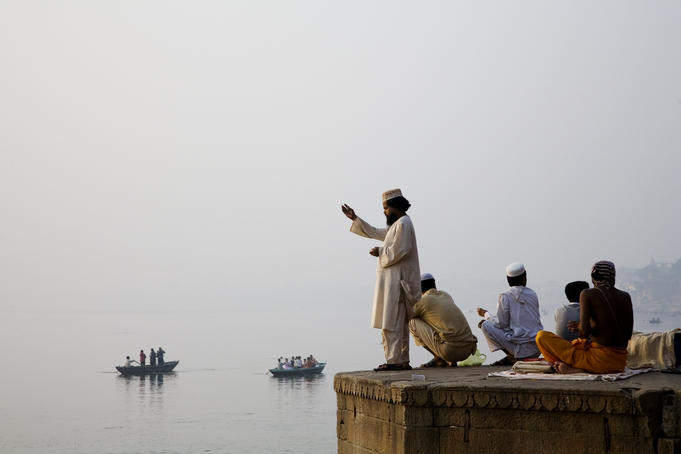 Men praying on the banks of the Ganges River at dawn.