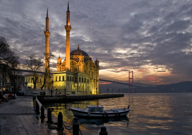 Ortakoy Mosque looking towards the Bosphorus Bridge, under a cloudy sky.