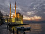 Ortakoy Mosque looking towards the Bosphorus Bridge, under a cloudy sky.