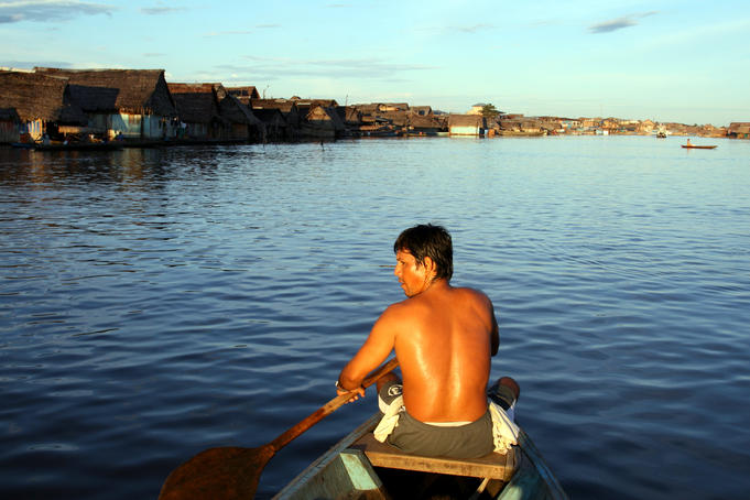 Man paddling on the Itaya River, with floating houses ahead, Belen neighbourhood.
