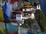 Taktshang Goemba or Tiger's Nest Monastery, perched on a steep cliff above the floor of Paro Valley, with fluttering prayer flags.