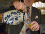 Man pouring Aeppler apple wine from Bembel Carafe.