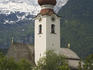 Church tower with snow capped mountains in the background.