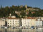 Boats in the harbour entrance with the old town walls on the hilltop in the distance.