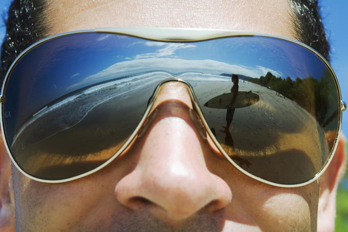 Reflections in shades of a surfer looking at the waves.