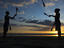Silhouetted jugglers on the beach.