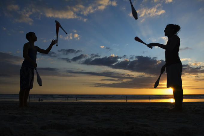 Silhouetted jugglers on the beach.