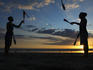 Silhouetted jugglers on the beach.