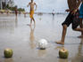 Boys playing beach football with coconut goal posts.