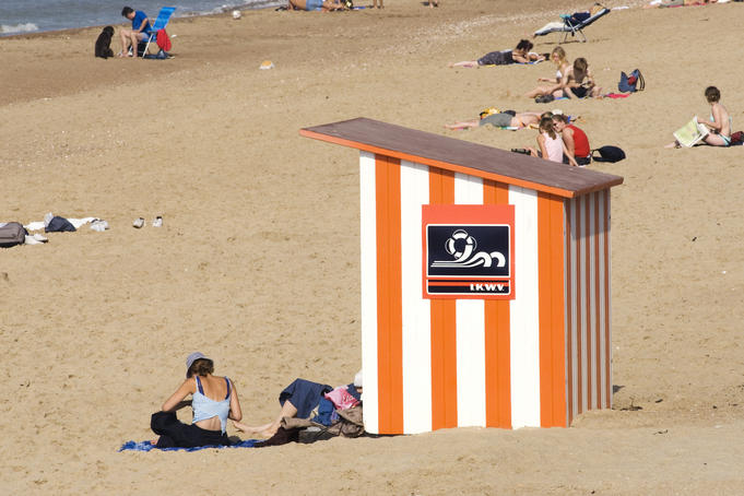 Wooden beach hut and sunbathers.