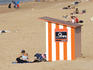 Wooden beach hut and sunbathers.