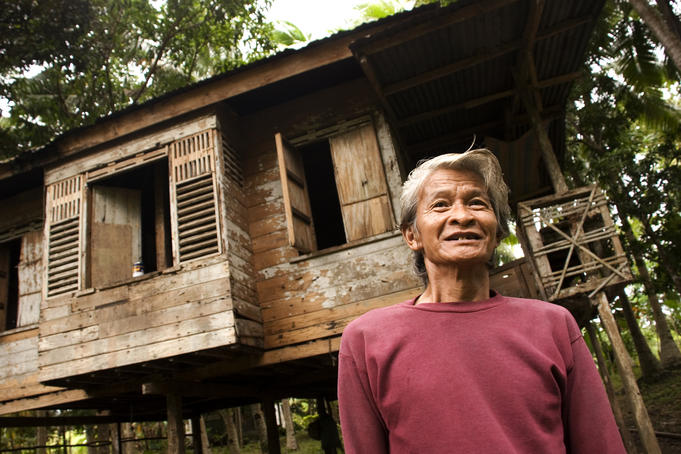 Man outside his rural wooden house.