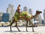 Tourist taking a camel ride on the beach in Dubai Marina.