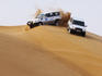 Jeeps negotiating sand dunes on jeep safari in Arabian Desert.