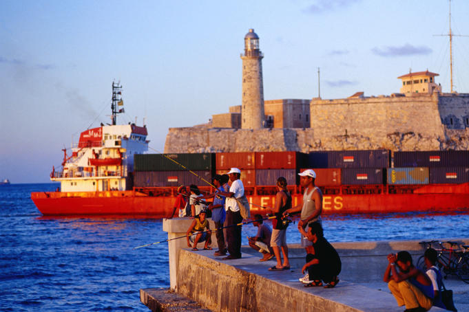 Fishing off the wharf in the Malecon across from the El Castillo del Morro, a cargo ship passing in between