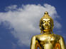 Torso and head detail of Buddha statue with backdrop of sky and cloud, near Chiang Rai.