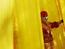Male costumed performer at the annual Sinulog Parade standing amidst bright yellow curtains.