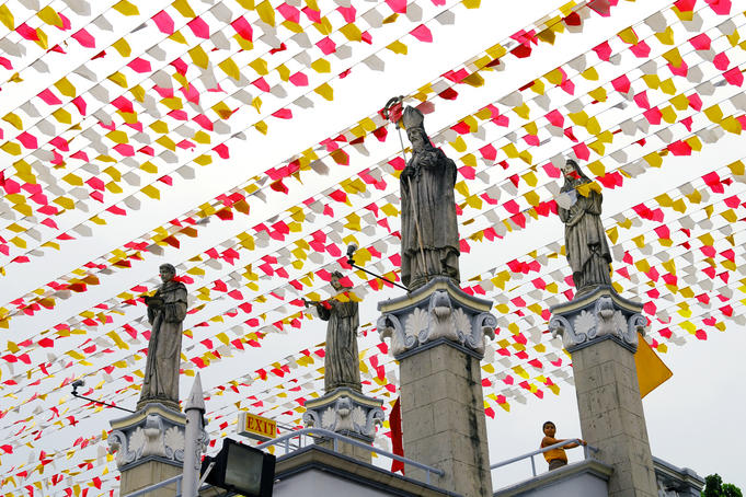 Statues at Basillica Minore del Santo Nino, with rows of flags overhead.