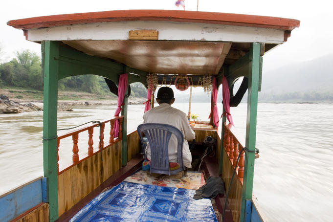 Boatman steering his boat along Mekong River.