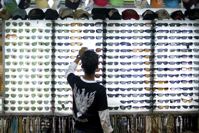 Customer at sunglass stall at Kata Beach evening market.
