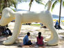 People sitting under dog statue on Patong Beach.