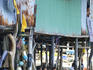 Group of men chatting under stilt huts at Ban Hua Thanon fishing village.