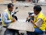 Motorcycle taxi drivers playing bottletop checkers.