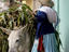 Woman loading donkey with eucalyptus leaves.