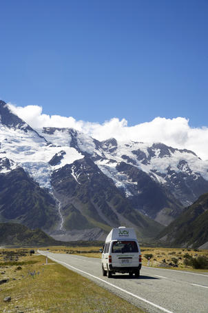 Campervan driving along road with Mt Sefton in background, Aoraki/Mt Cook National Park.