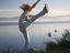 Girl high-kicking with sea in background.