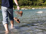 Hiker crossing stream with boots off.
