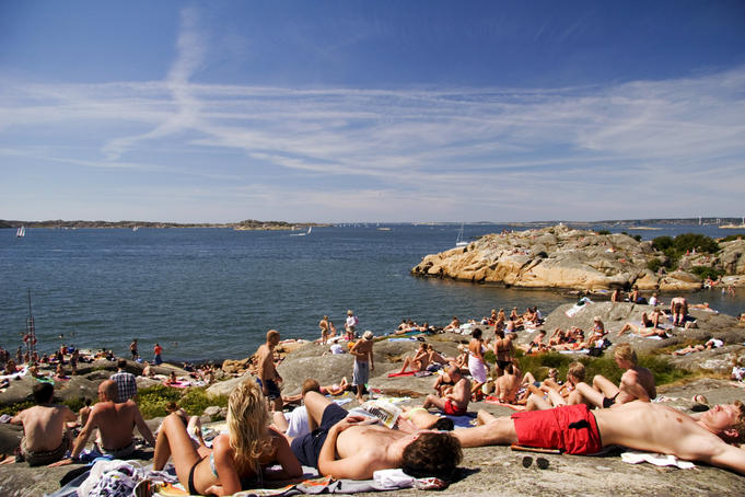 People sprawled on rocks by sea during summer.