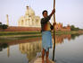 Boatman poling across Yamuna River beside Taj Mahal.